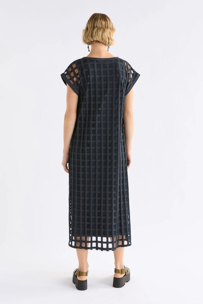Woman wearing a dark blue checkered dress on a white background. Elk Grid Burnout Dress in Space Blue.