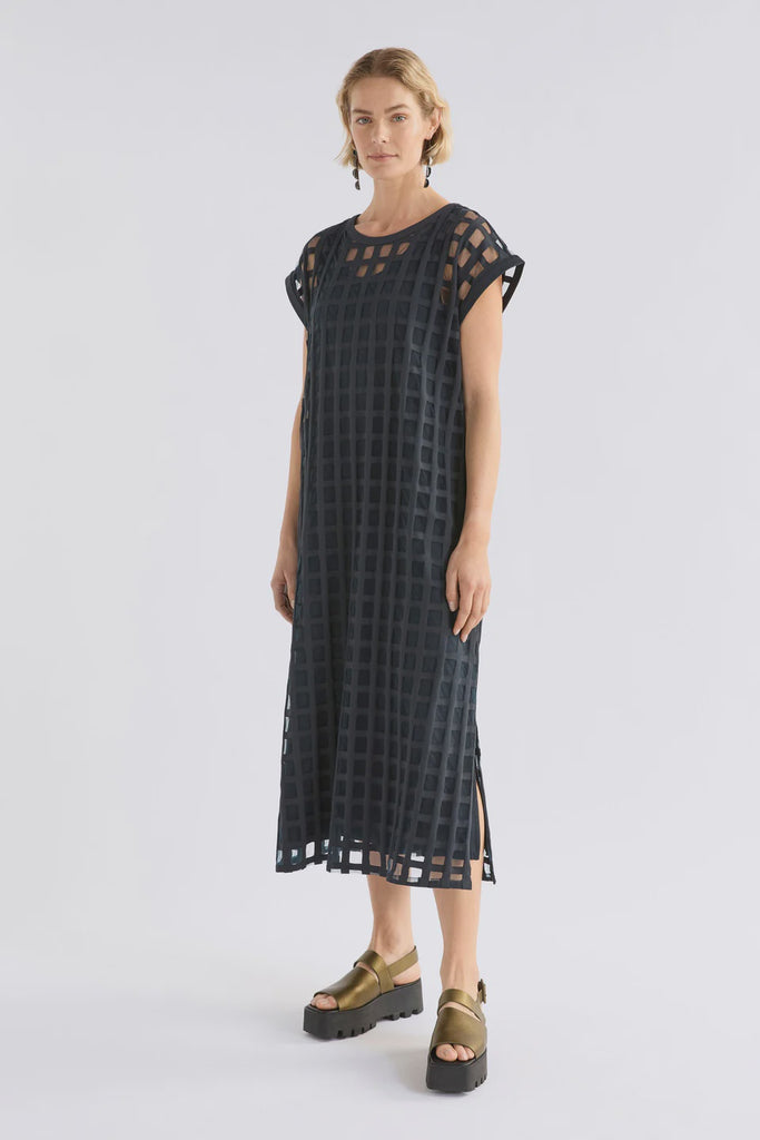 Woman wearing a dark blue checkered dress on a white background. Elk Grid Burnout Dress in Space Blue.