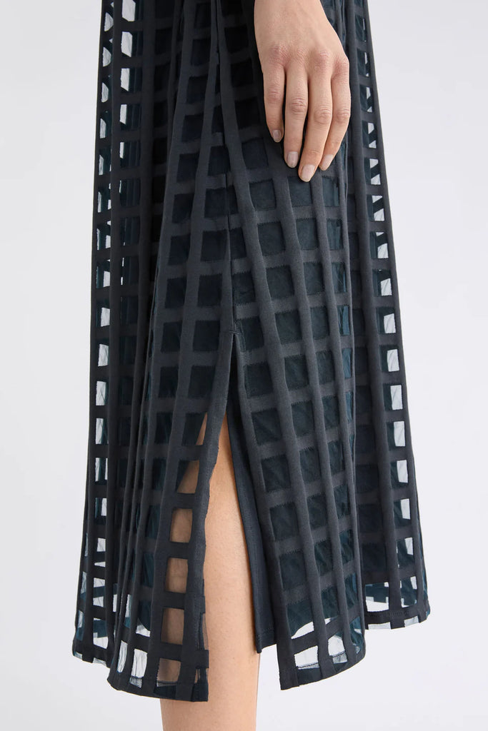 Woman wearing a dark blue checkered dress on a white background. Elk Grid Burnout Dress in Space Blue.