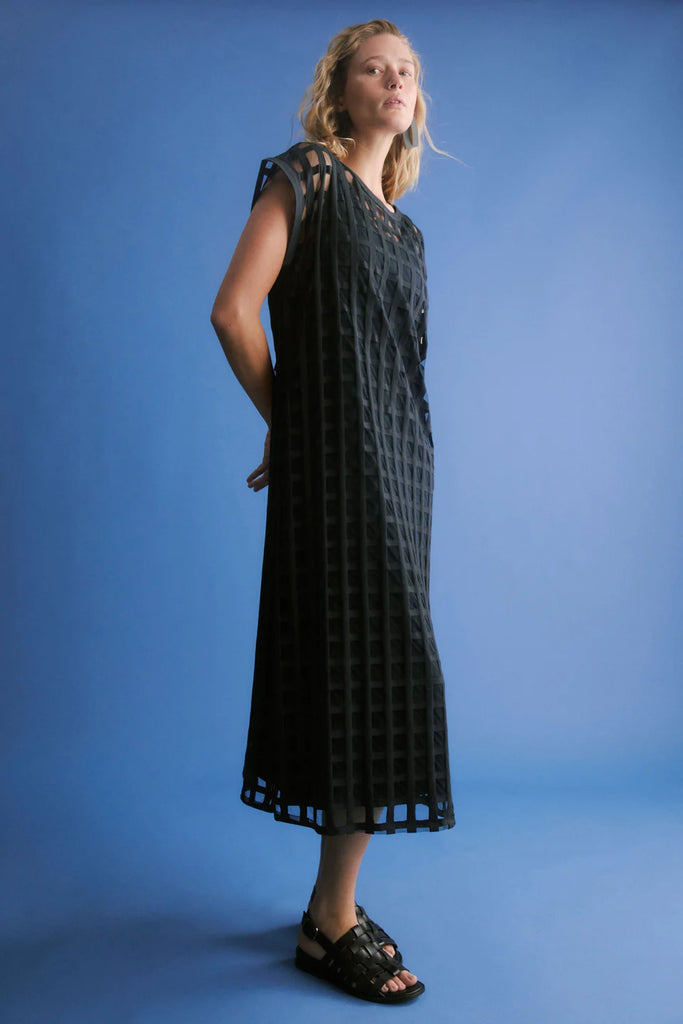Woman wearing a dark blue checkered dress on a blue background. Elk Grid Burnout Dress in Space Blue.
