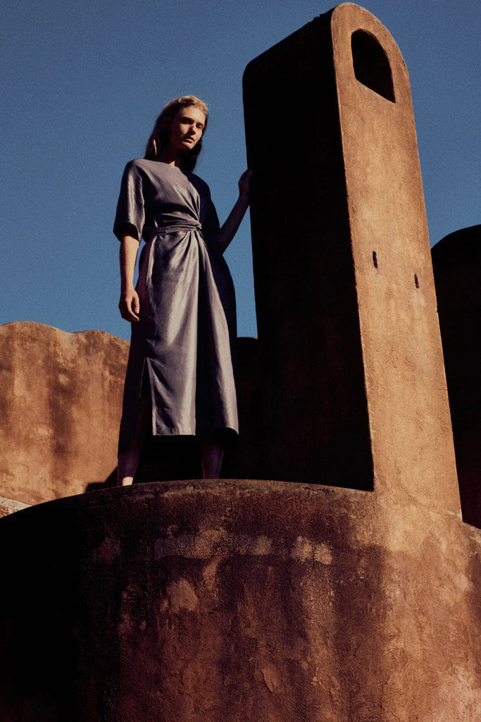 Woman wearing a gray dress with an industrial background. Elk Lissu dress