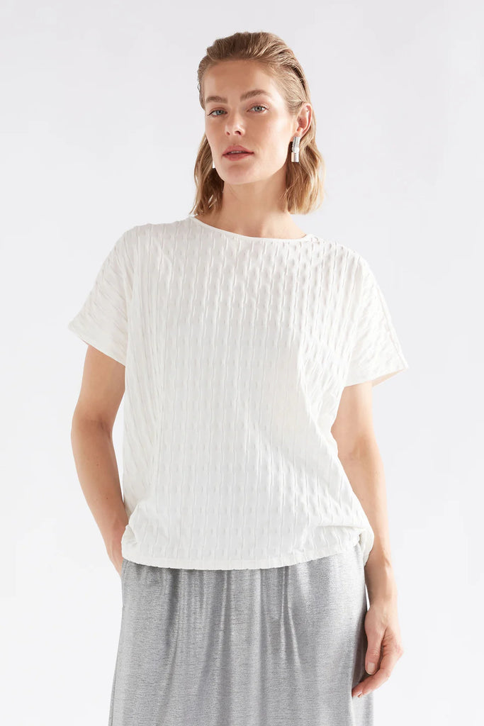 Woman wearing an Elk white textured top against a light background called the Orta T Shirt in white