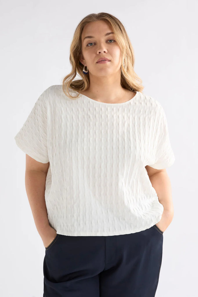 Woman wearing an Elk white textured top against a light background called the Orta T Shirt in white