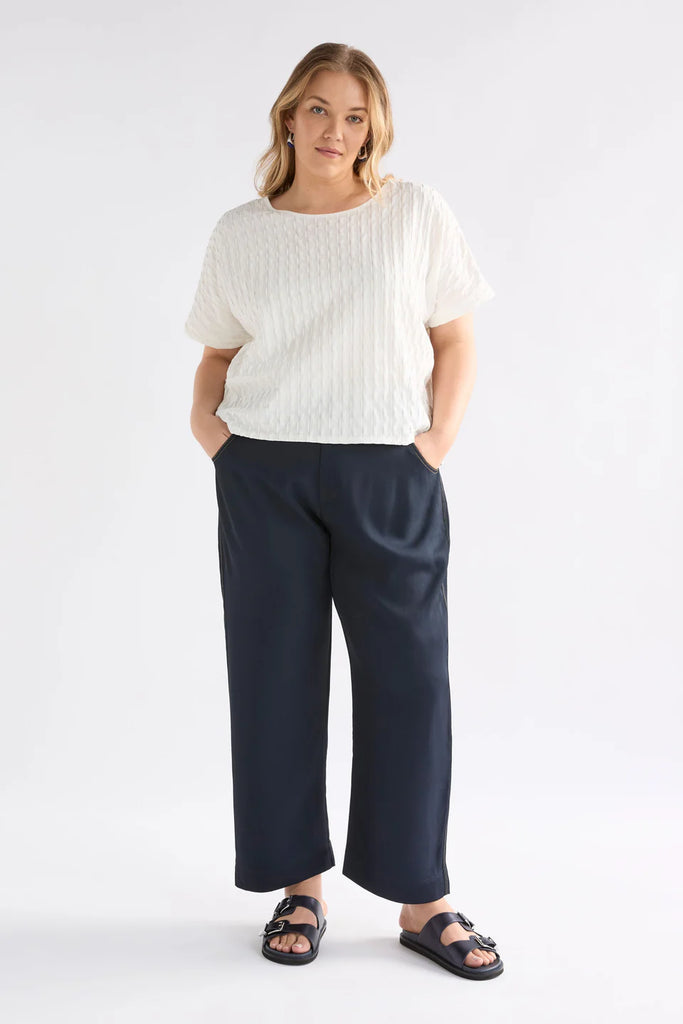 Woman wearing an Elk white textured top against a light background called the Orta T Shirt in white