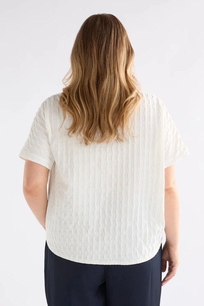Woman wearing an Elk white textured top against a light background called the Orta T Shirt in white