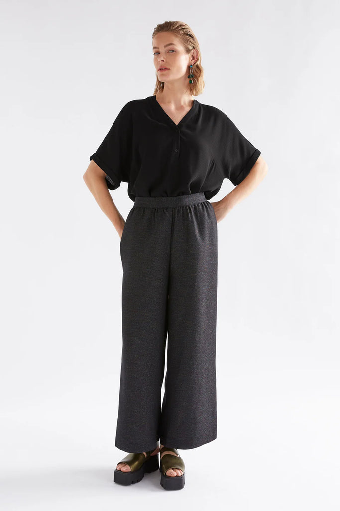 Person wearing a black sparkly outfit against a white background. Elk Tulle Pant and Top.