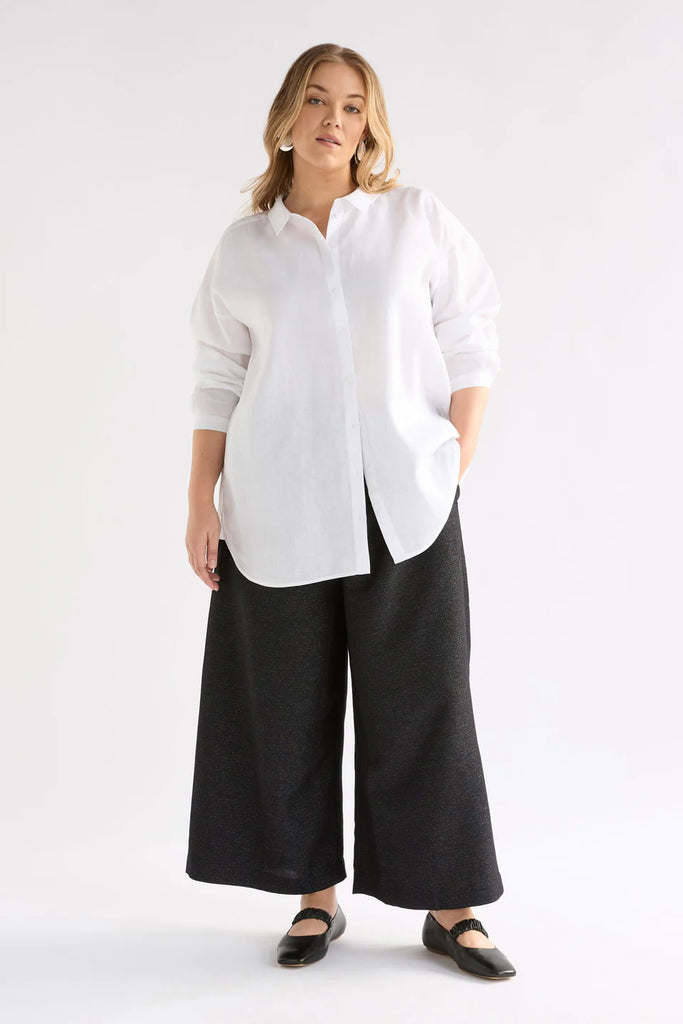 Person wearing a black sparkly pant and white shirt against a white background. Elk Tulle Pant.