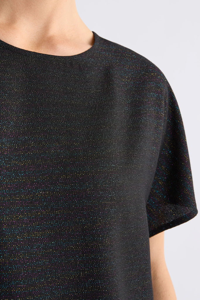 Woman wearing a black sparkly top on a light grey background