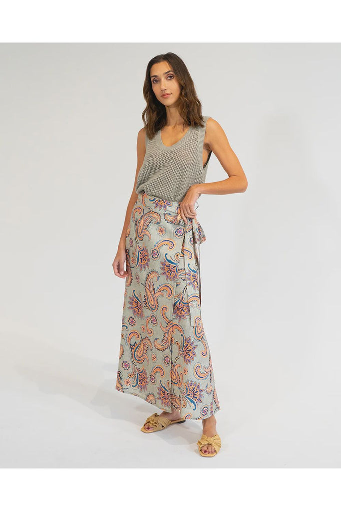 Woman wearing a patterned skirt and sleeveless top on a white background. Elms & King La Rocco Skirt in paisley print.