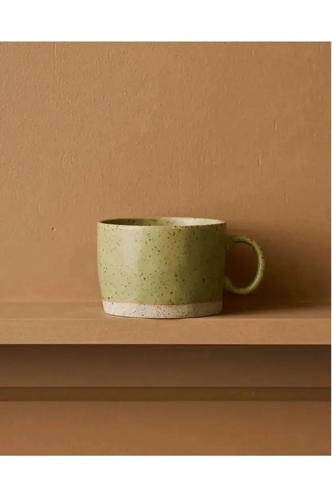 Set of 4 Emerald Mineral Mugs by Robert Gordon. These green speckled ceramic mugs feature a reactive glaze on a brown surface, set against a brown background.