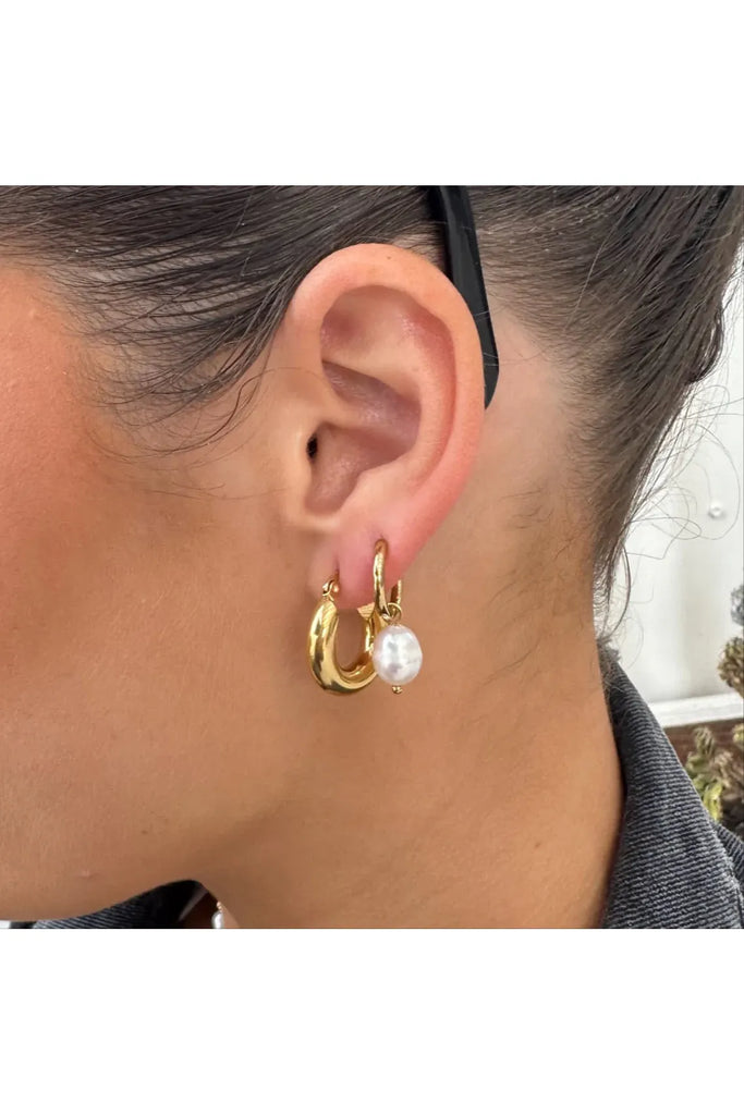 Gold hoop earrings with a pearl accent worn by a person. After Dark Pearl Hoop Earrings in gold by Ever