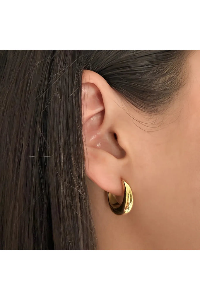 Close-up of a person wearing a gold hoop earring with dark hair. Ever Empire Hoop Earrings.
