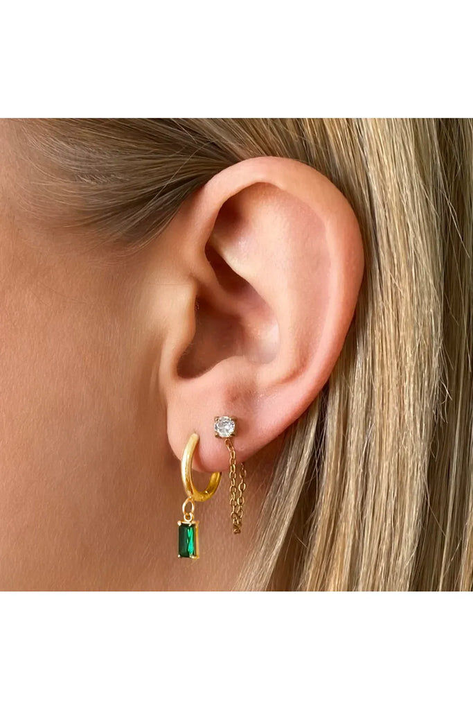 Close-up of an ear wearing gold hoop earrings with green gemstone and clear stone.Ever Luxe Gold Drop Earrings in Emerald 