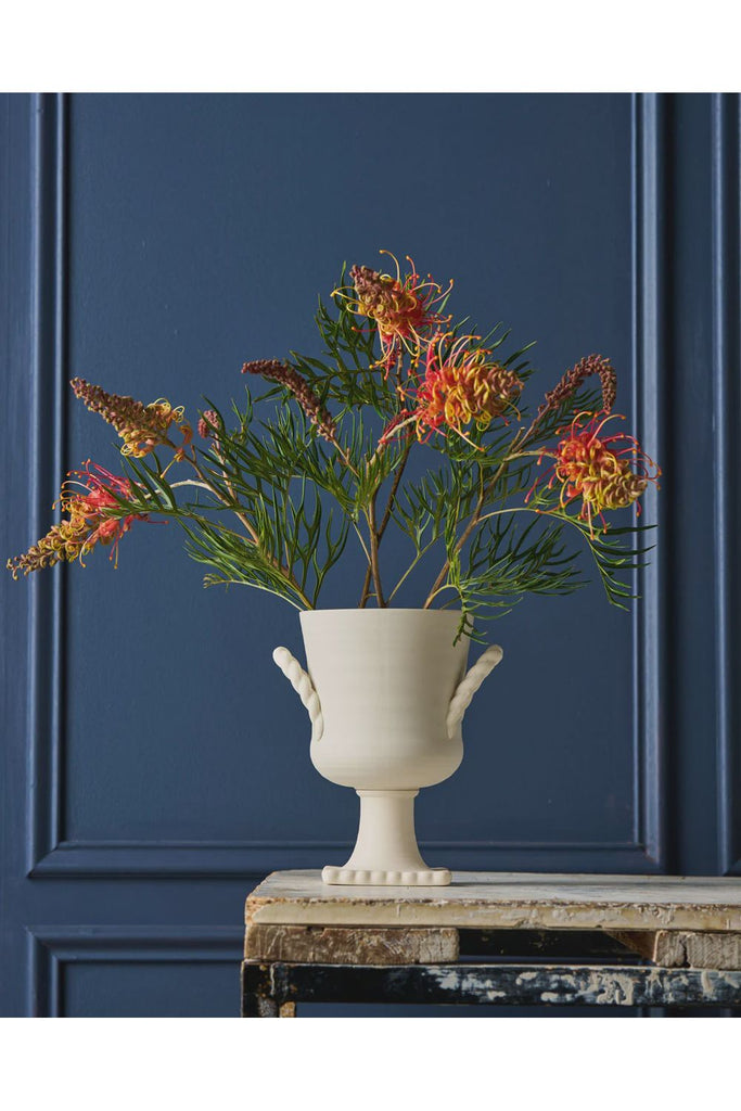 Robert Gordon Trophy Life Collection Florence Vase. White vase with red and yellow flowers against a blue panelled wall.