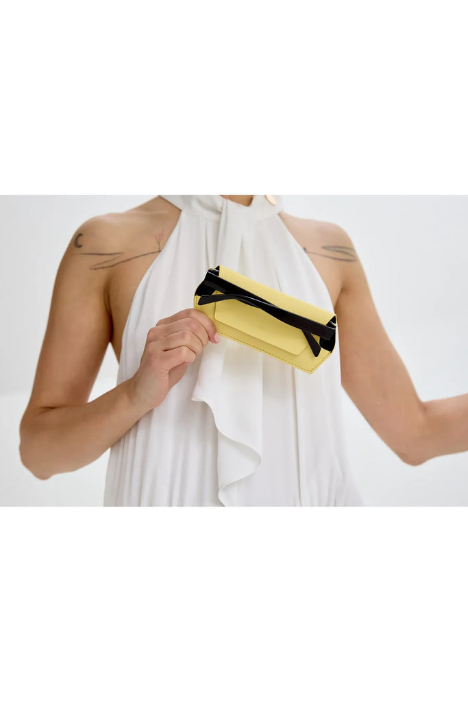 Person holding a yellow glasses case with a white background