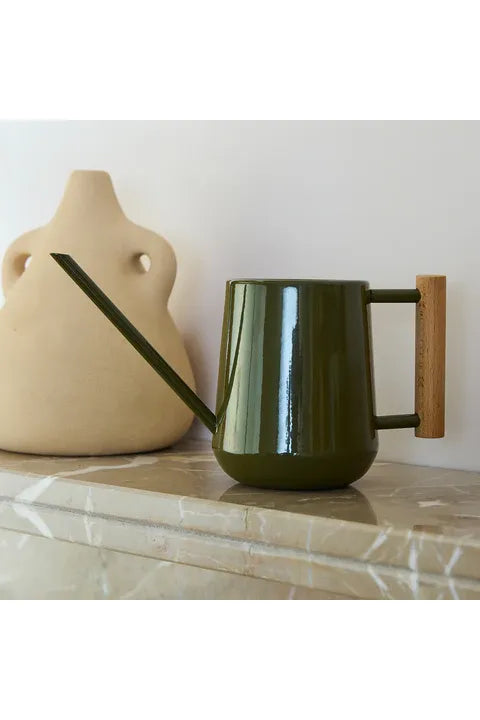 Burgon & Ball Olive Green Collector Indoor Watering Can with a Wooden Handle on a marble surface.