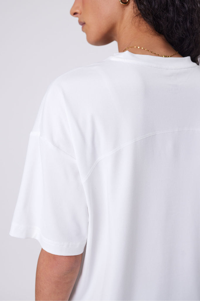 Woman wearing a white t-shirt on a plain background. Marlow Half time tee in Ivory short sleeve.