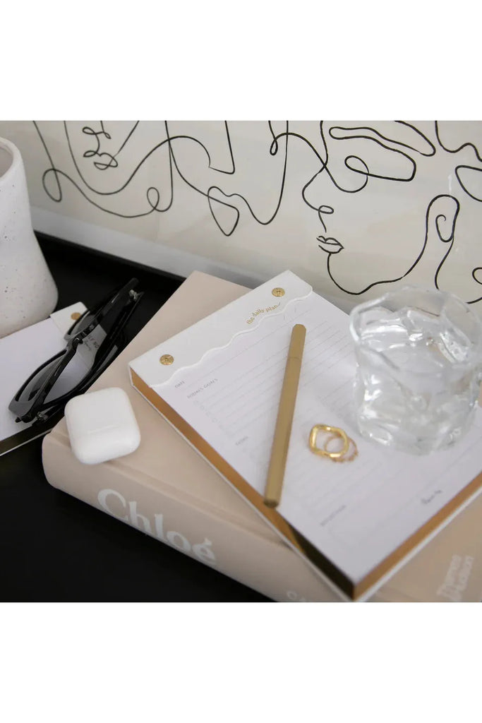Papier HQ Curved Daily Notepad Nude sitting on desk underneath pen, rings and water glass