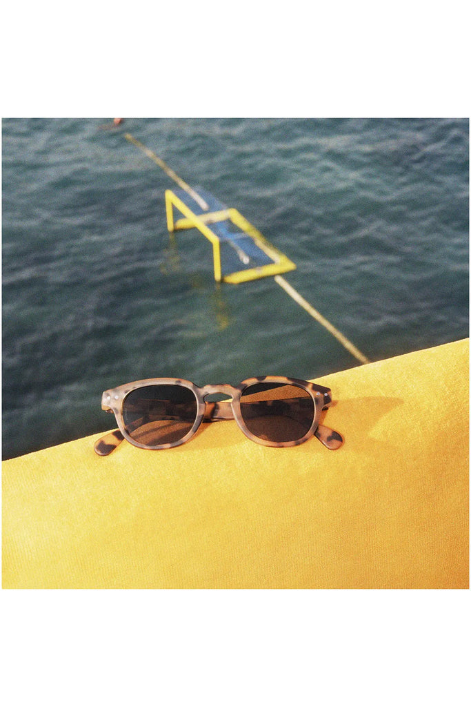 Izipizi Polarised Sunglasses Frame Shape C Light Tortoise Glasses sitting placed on a pool towel