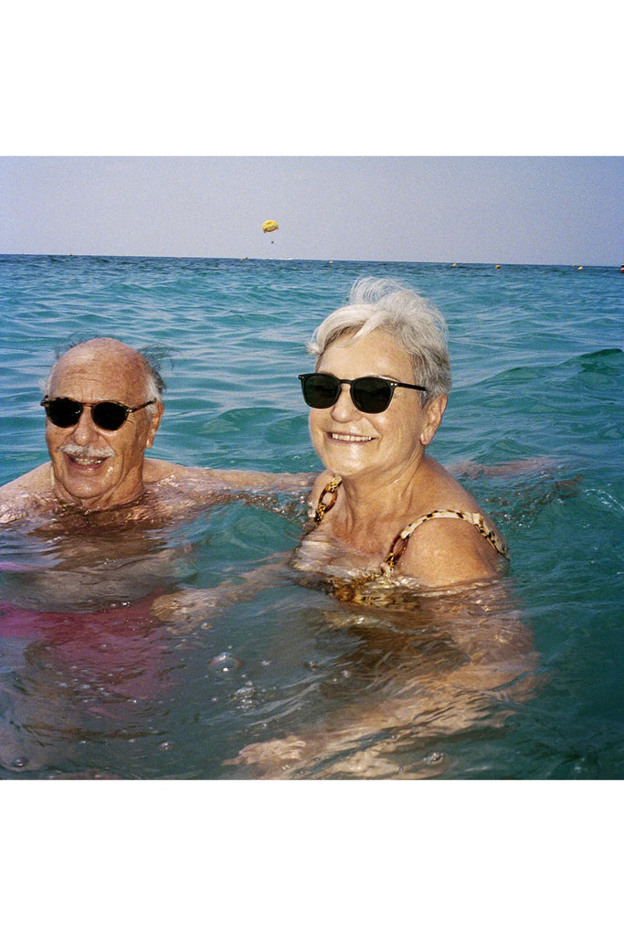 Izipizi Polarised Sunglasses Sun Collection Frame Shape E Black  + Frame Shape D Tortoise being worn by a couple floating in the ocean