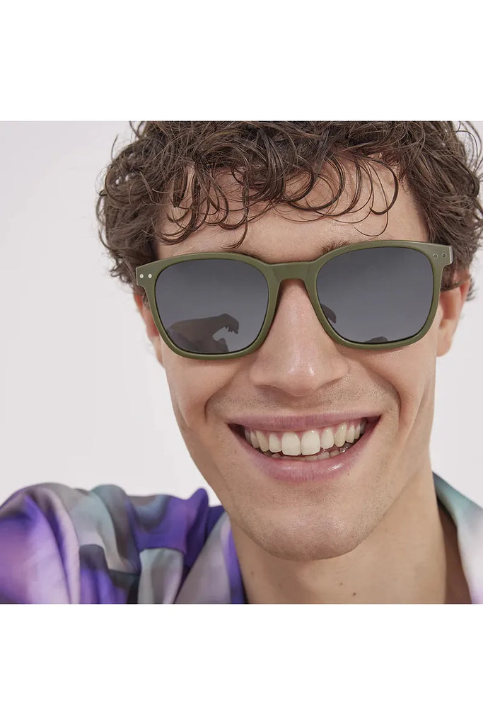 A man wearing Izipizi khaki green polarised sunglasses against a neutral background.