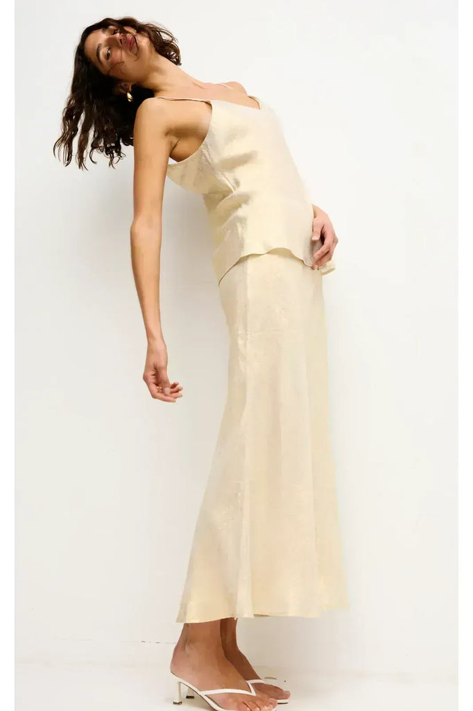 Woman wearing a gold top and long skirt on a white background. Kinney Gia Skirt in gold lurex.