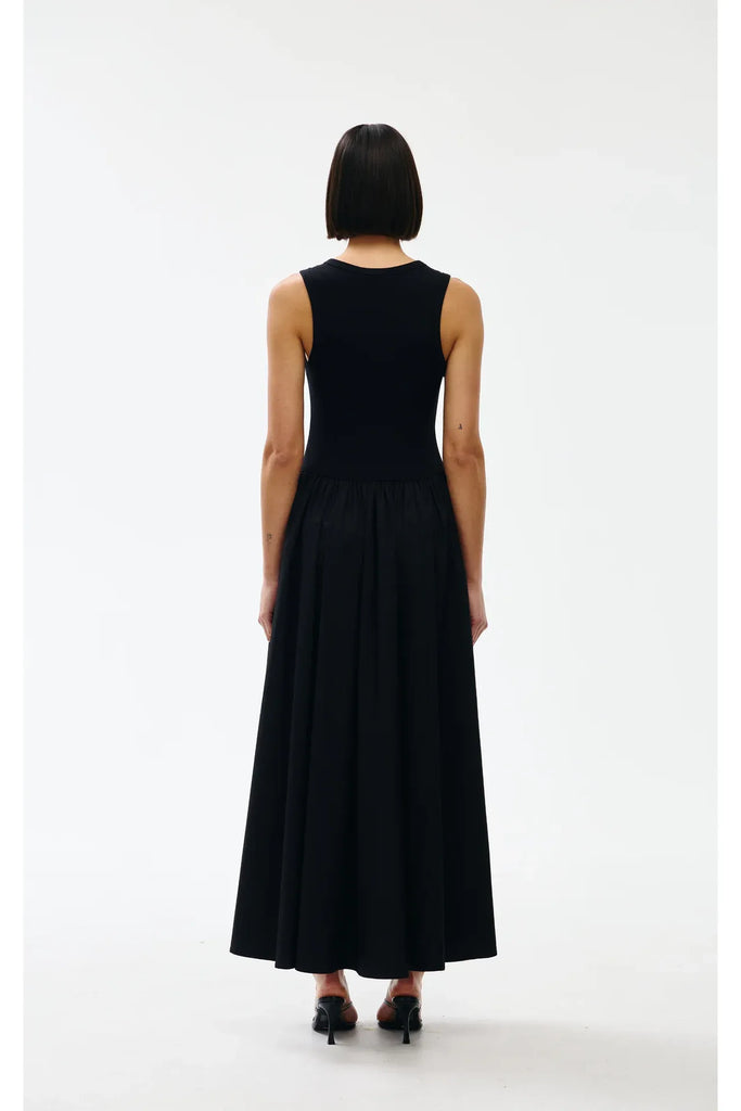 Woman wearing a black sleeveless dress on a white background. Kinney Hallie Dress in black.