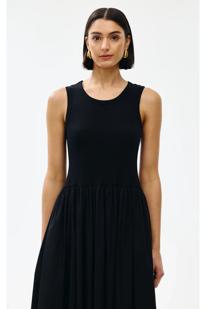Woman wearing a black sleeveless dress on a white background. Kinney Hallie Dress in black.