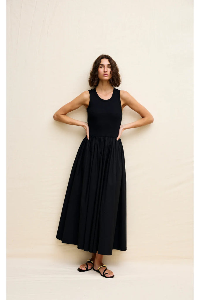 Woman wearing a black sleeveless dress on a white background. Kinney Hallie Dress in black.