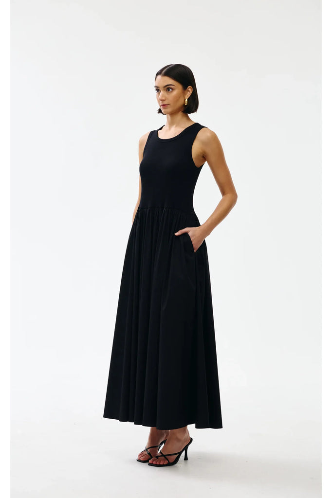 Woman wearing a black sleeveless dress on a white background. Kinney Hallie Dress in black.