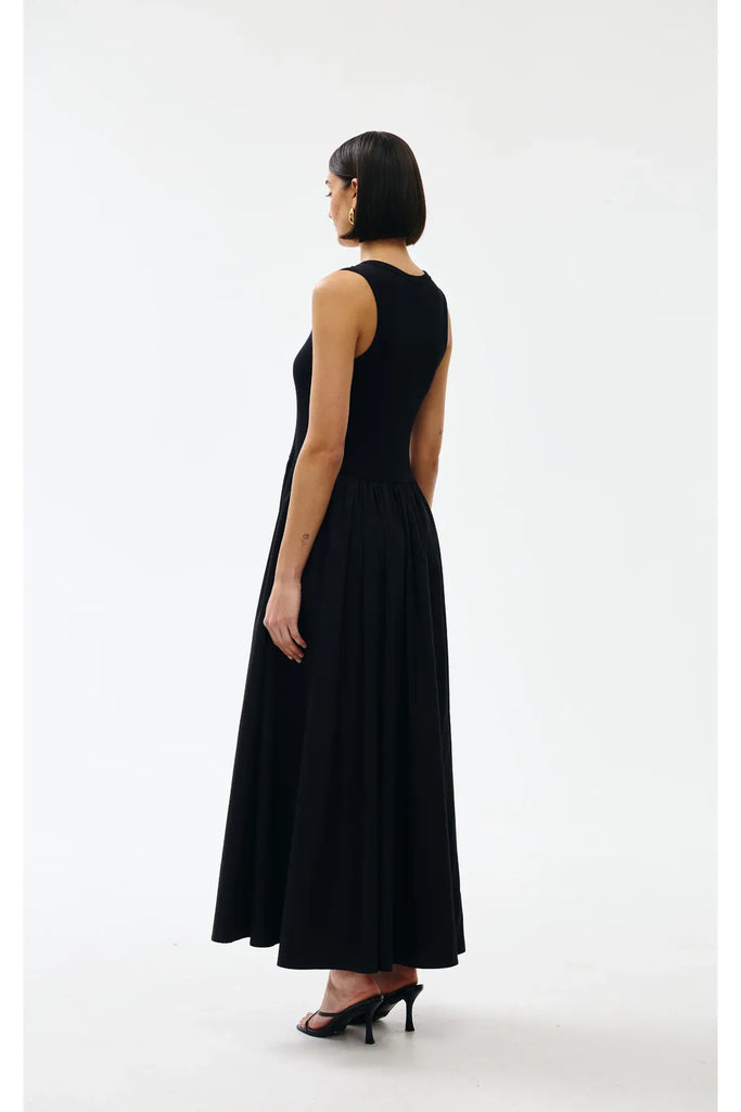 Woman wearing a black sleeveless dress on a white background. Kinney Hallie Dress in black.