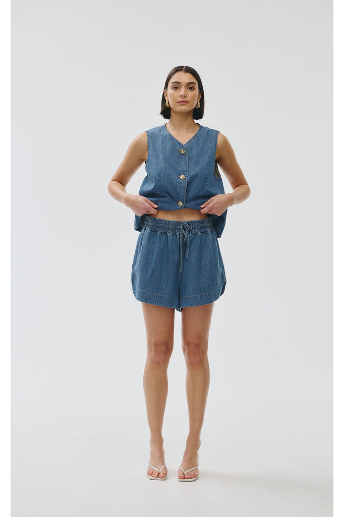 Woman wearing a blue denim outfit on a white background. Kinney Juniper Shorts