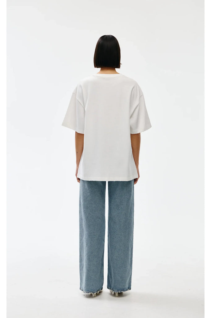 Person wearing a white oversized t-shirt and blue jeans on a white background