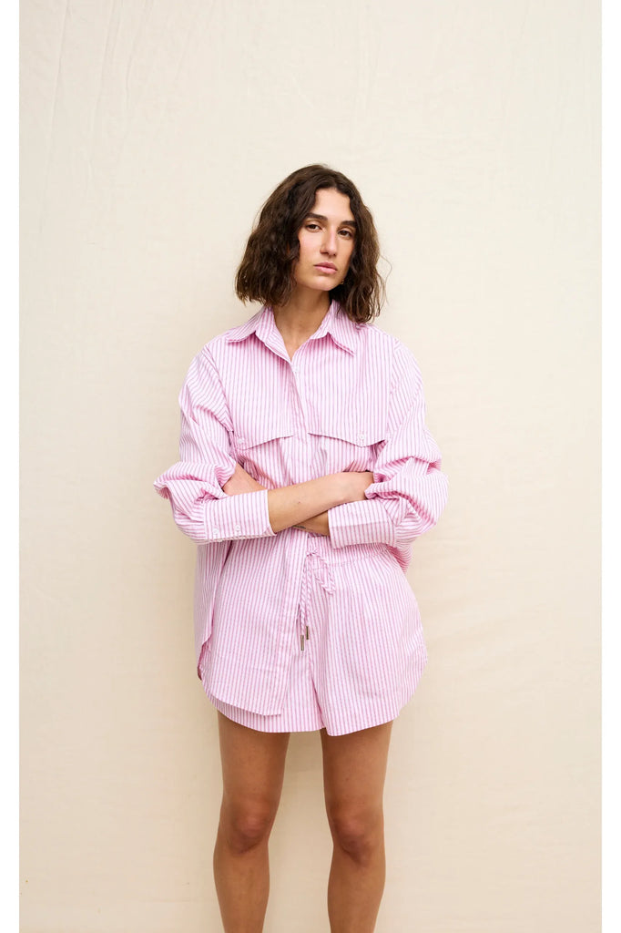 Person wearing a pink striped shirt on a beige background