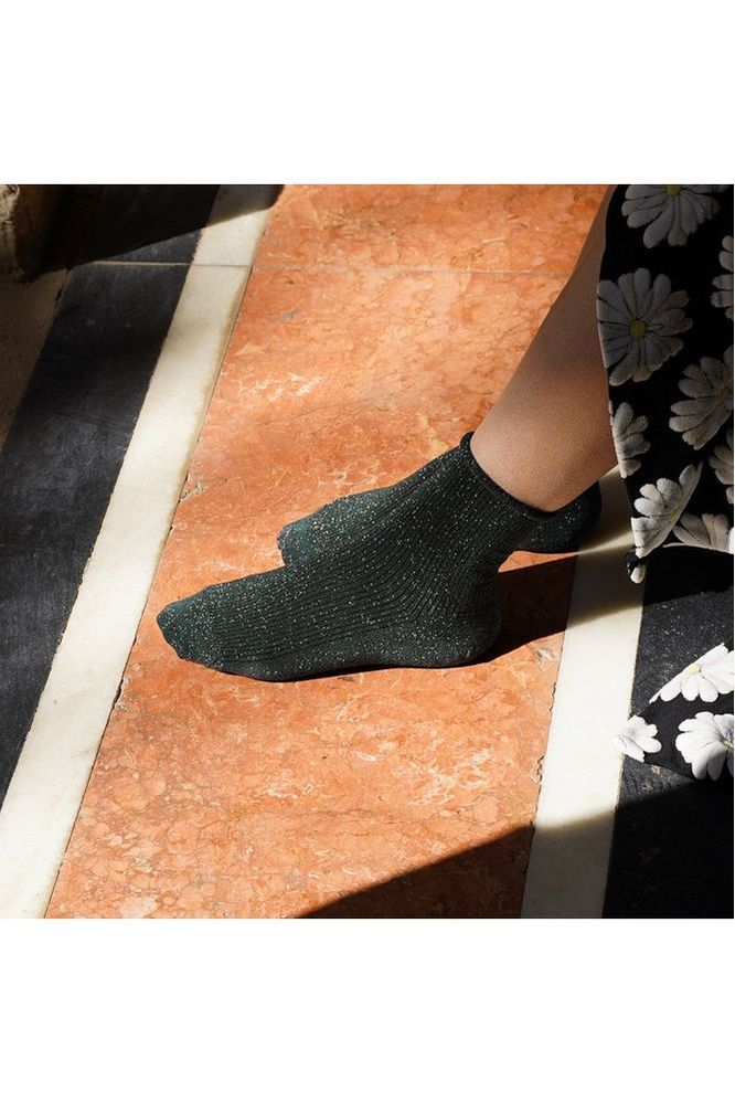 Person wearing Klue Green Glitter Lurex socks on a patterned floor