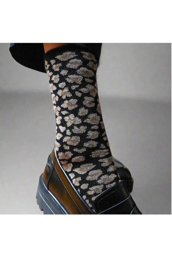 Klue Leopard print sock on a foot wearing a black shoe against a neutral background
