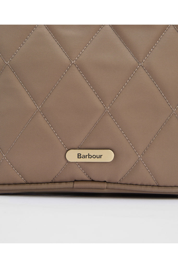 Quilted beige handbag on a light gray background. Barbour Quilted crossbody bag in sand.