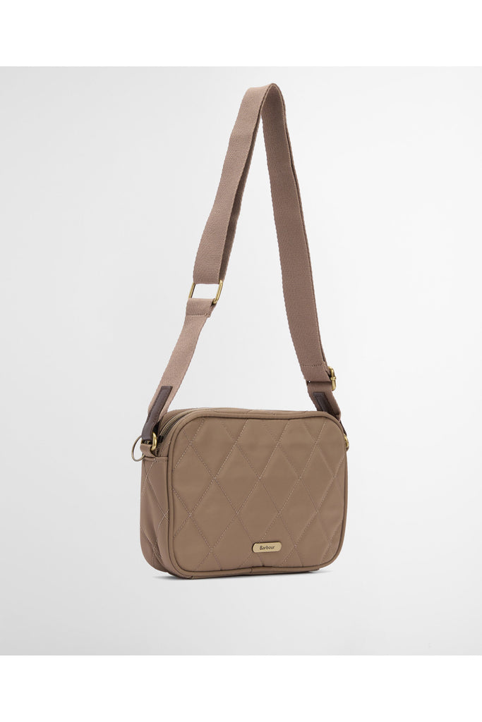 Quilted beige handbag on a light gray background. Barbour Quilted crossbody bag in sand.