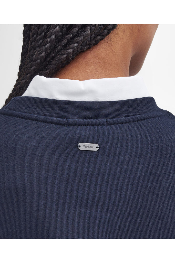 Person wearing a navy Barbour sweatshirt with a white collar on a light gray background. Northumberland Sweatshirt in Navy and Cloud.