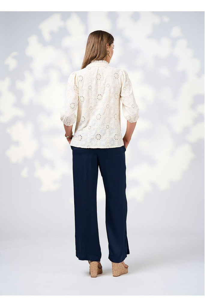 Woman wearing a Loobies Story Jada Pant in Indigo with a white blouse and sandals