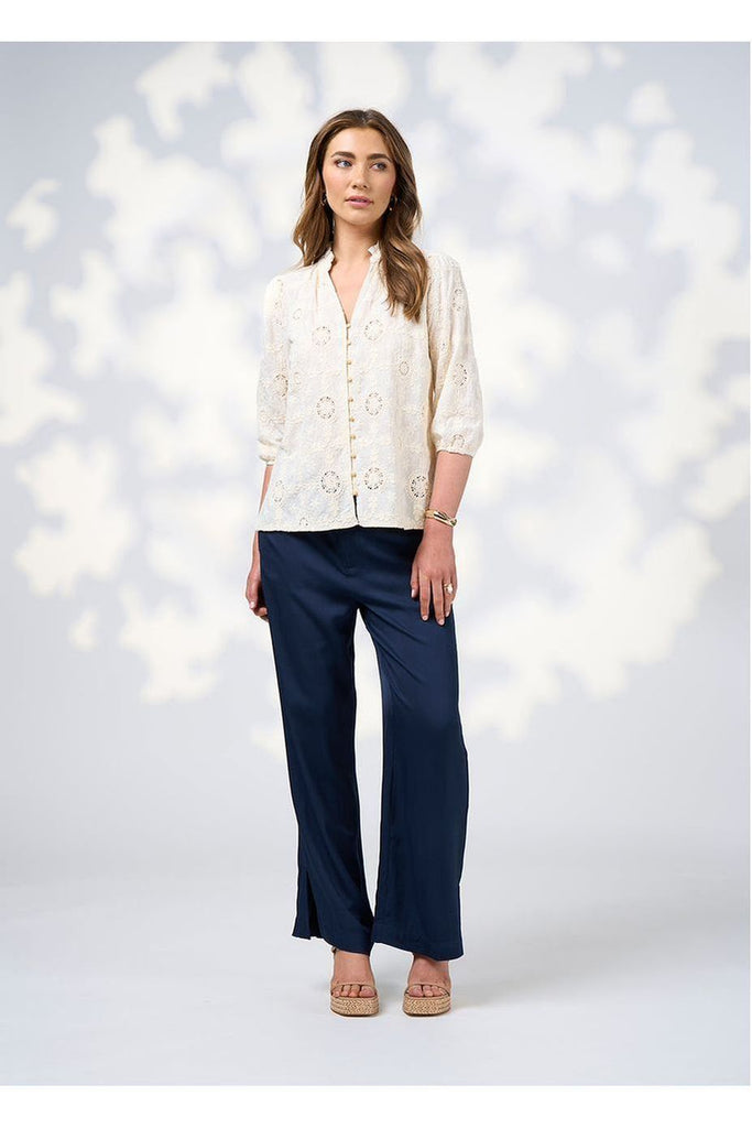 Woman wearing a Loobies Story Jada Pant in Indigo with a white blouse and sandals