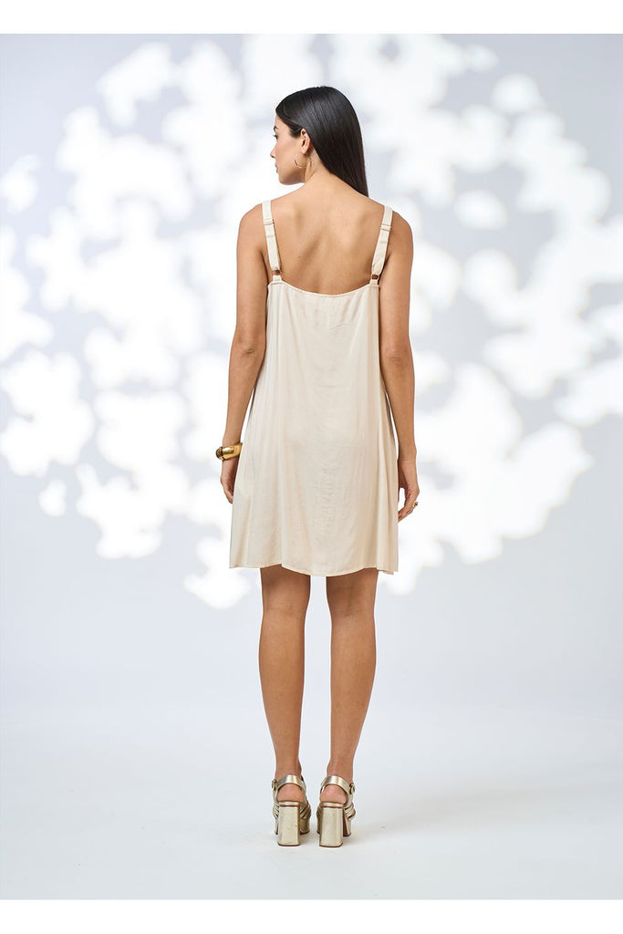 Woman wearing a beige slip dress against a white background. Loobies Story Slip dress in nude.
