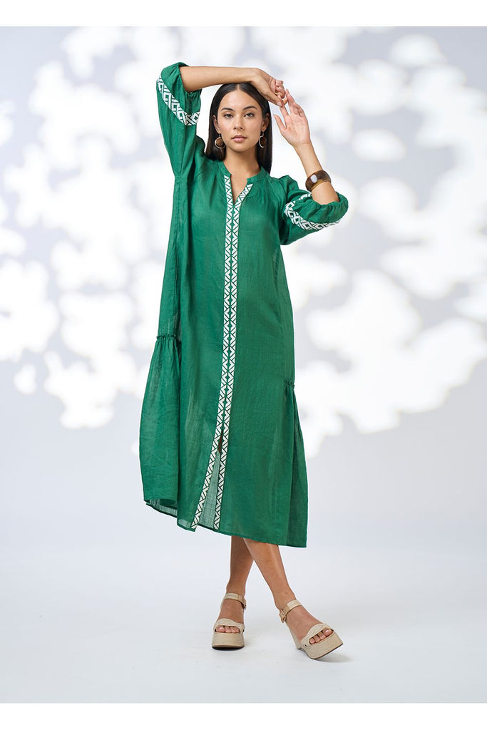Woman wearing a green dress with white embroidery on a white background. Loobies Story Maya Midi dress in Palm Green.