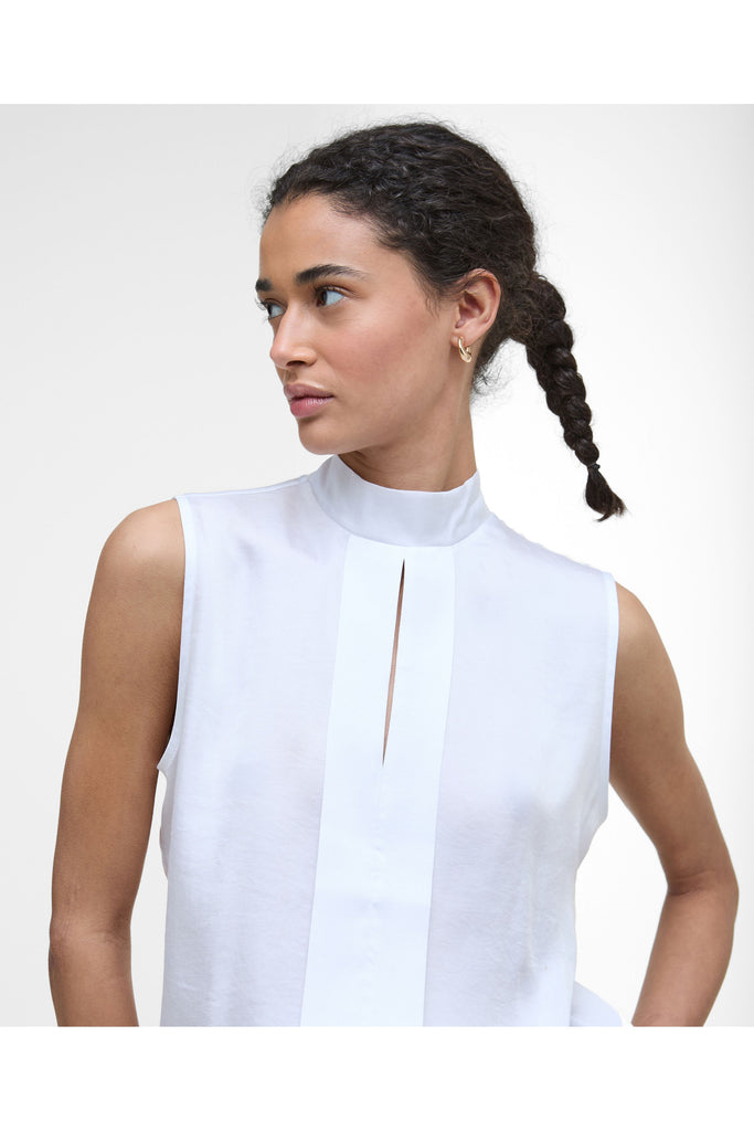Woman wearing a white sleeveless top and black pants on a plain background. Barbour Sophia Top in White.