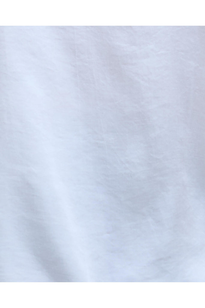 Woman wearing a white sleeveless top and black pants on a plain background. Barbour Sophia Top in White.