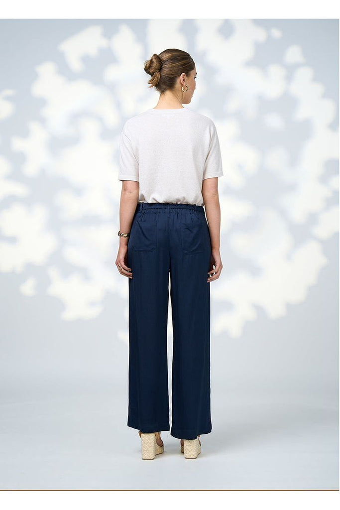 Woman wearing a Loobies Story Jada Pant in Indigo with a white top and sandals