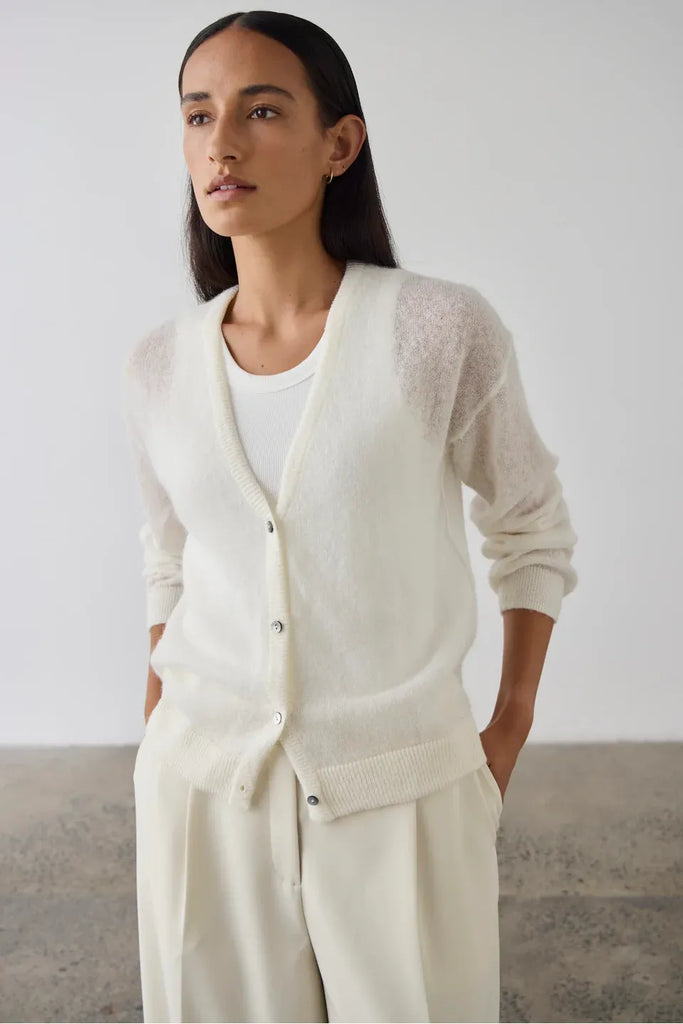 Woman wearing a cream cardigan over a white tank and pants. Laing Fine Alpaca Cardigan in Cream.
