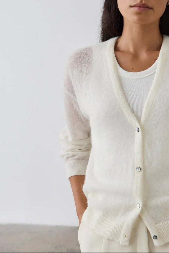 Woman wearing a cream cardigan over a white tank and pants. Laing Fine Alpaca Cardigan in Cream.