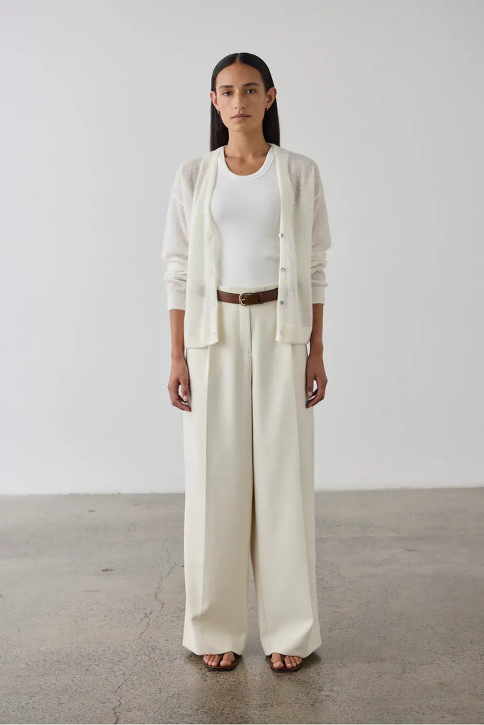 Woman wearing a cream cardigan over a white tank and pants. Laing Fine Alpaca Cardigan in Cream.