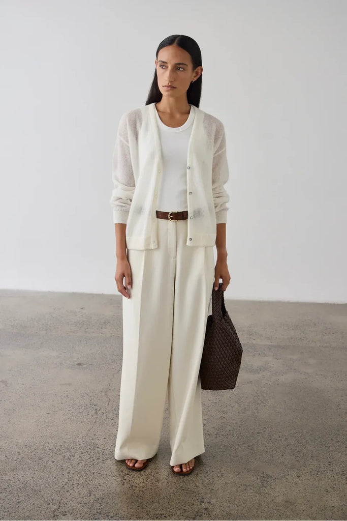 Woman wearing a cream cardigan over a white tank and pants. Laing Fine Alpaca Cardigan in Cream.